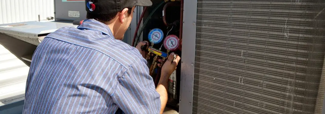 HVAC technician servicing a condenser unit in Hannibal